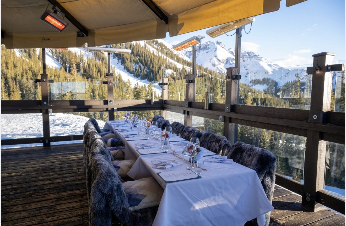 A long table set for a private group on the heated deck at Bon Vivant, fur throws over the chairs and the San Juan peaks beyond